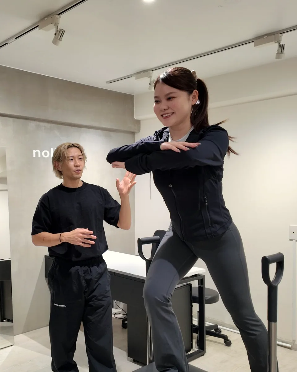 ピラティスチェアに片足を乗せて動くお客様と、そばで声をかけるトレーナー｜パーソナルジムnoll-ett渋谷店