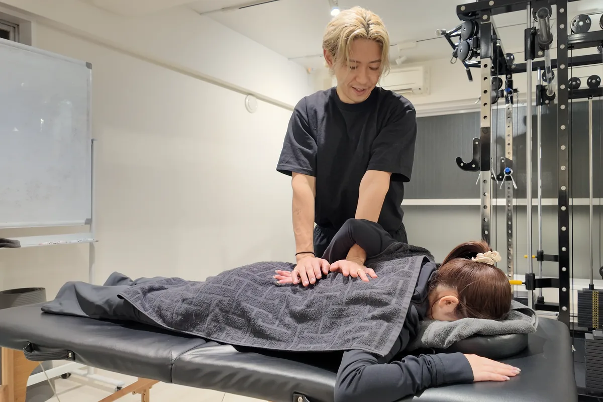 施術台にうつ伏せになったお客様の背中を、トレーナーが手で整えている様子｜パーソナルジムnoll-ett渋谷店